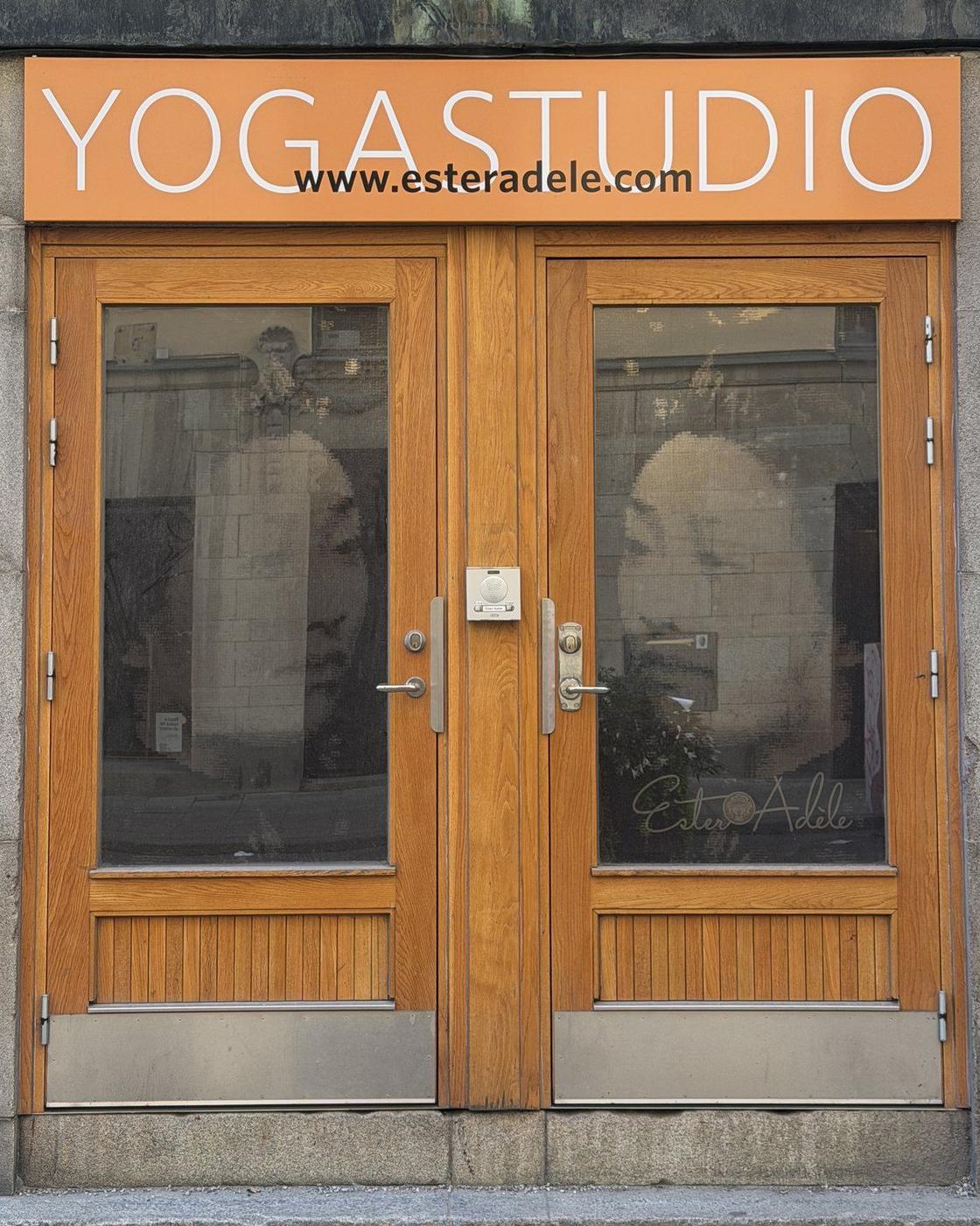 The entrance to Ester Adèle on Sankt Paulsgatan: wooden double doors under an orange YOGASTUDIO sign