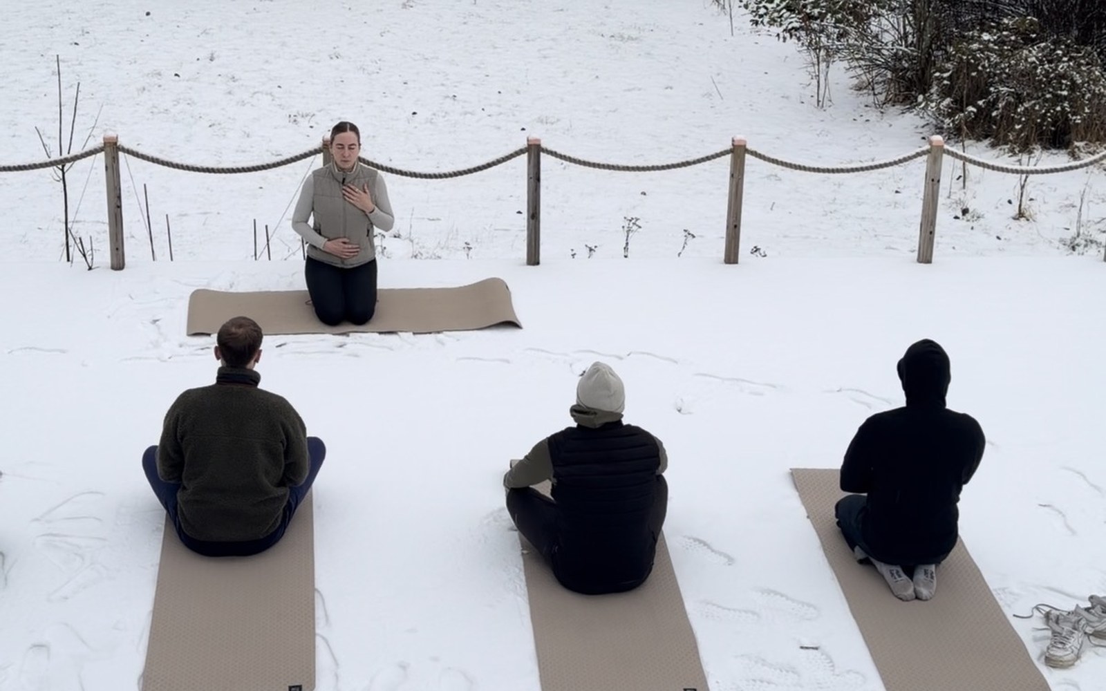 An outdoor yoga session in the snow for a tech company, participants sitting on mats facing the teacher